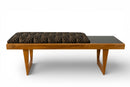 A Bench With a Cushioned Seat and Glass Table Top