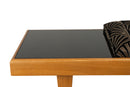 A Bench With a Cushioned Seat and Glass Table Top